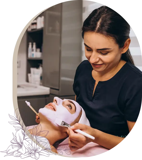 Smiling esthetician applying a facial mask with a brush to a relaxed client, part of a hydrating facial at a beauty and wellness spa.